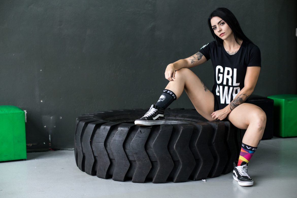 Mulher sentada em pneu com camiseta KVRA